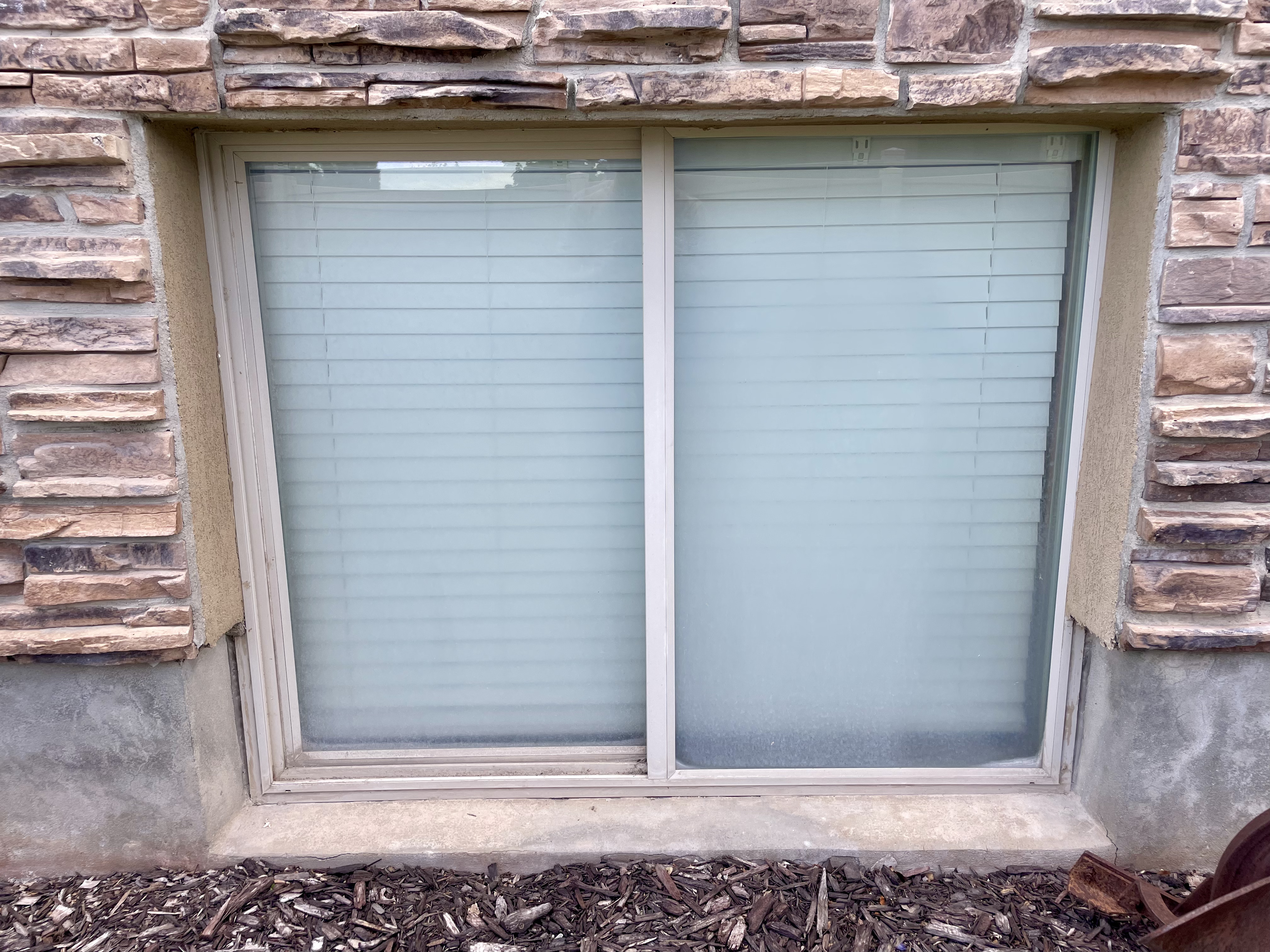 Basement sliding window covered in hard water deposits before cleaning